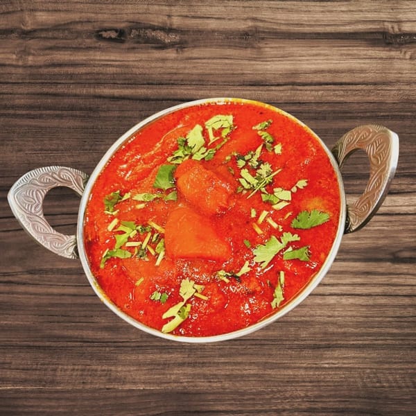 Turmeric Hut's vibrant red Indian curry, garnished with fresh cilantro, in a decorative silver bowl.