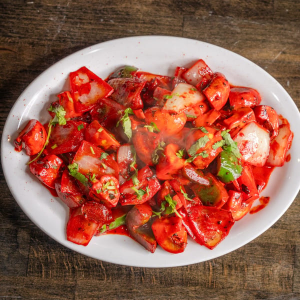 Indian chili paneer, a vibrant red dish with paneer, onions, and bell peppers, garnished with cilantro.